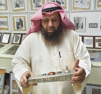 د . محمد بن إبراهيم الشيباني يعاين محبرة أثرية من مقتنيات مركز المخطوطات والتراث