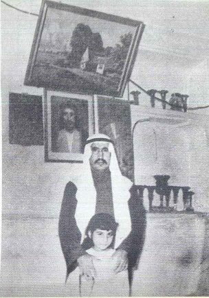 سيف مرزوق الشملان - يرحمه الله - في داره القديمة في شرق بمدينة الكويت يقف تحت صورته سنة 1954 م 