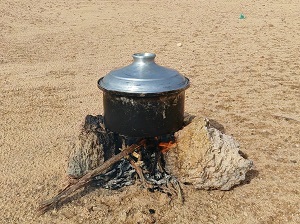 طبخ الطعام في قدر على الحجارة بالصحراء 