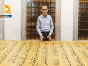الخطاط العراقي علي زمان ييقف أمام أكبر مصحف خطه بيده في العالم 