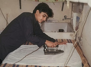 احد شباب اللجان الشعبية في كيفان يتولى كوي ملابس الزبائن بعد فرار العمالة ابان عزو العراق للكويت